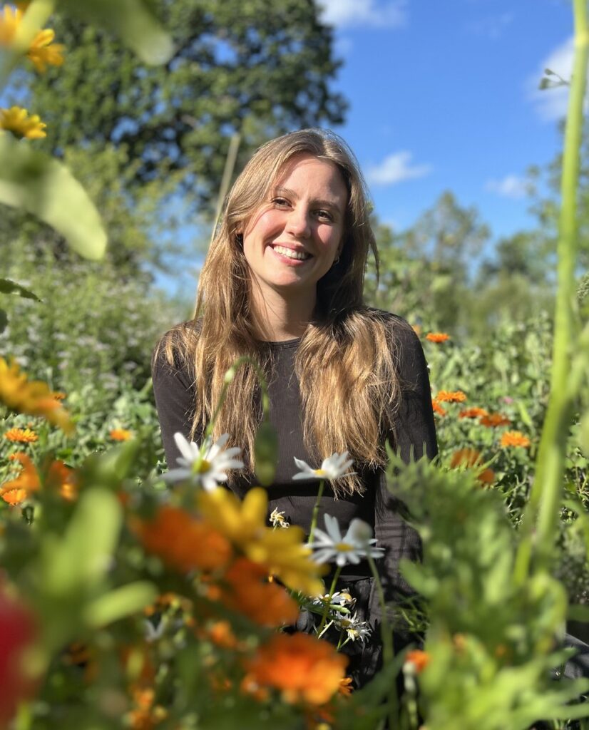 Jara lächelnd zwischen blühenden Ringelblumen und Margeriten
