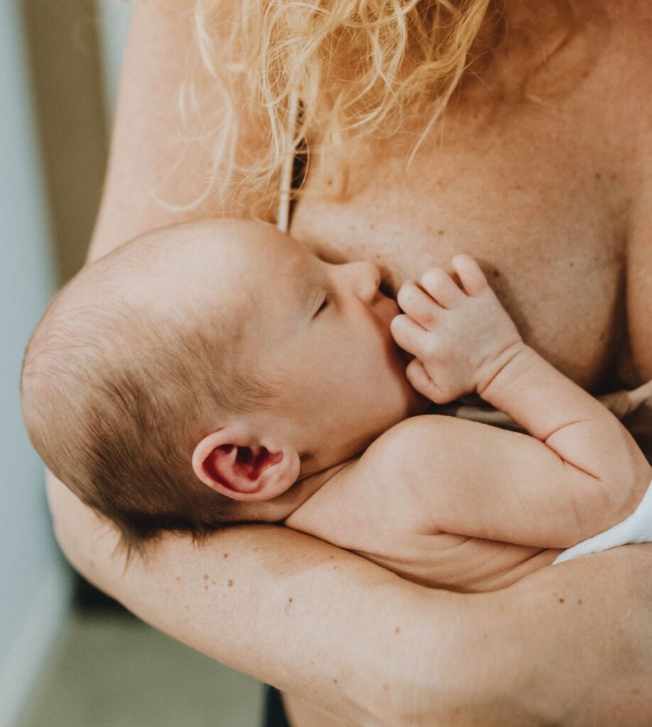 Neugeborenes stillt auf der Brust seiner Mutter